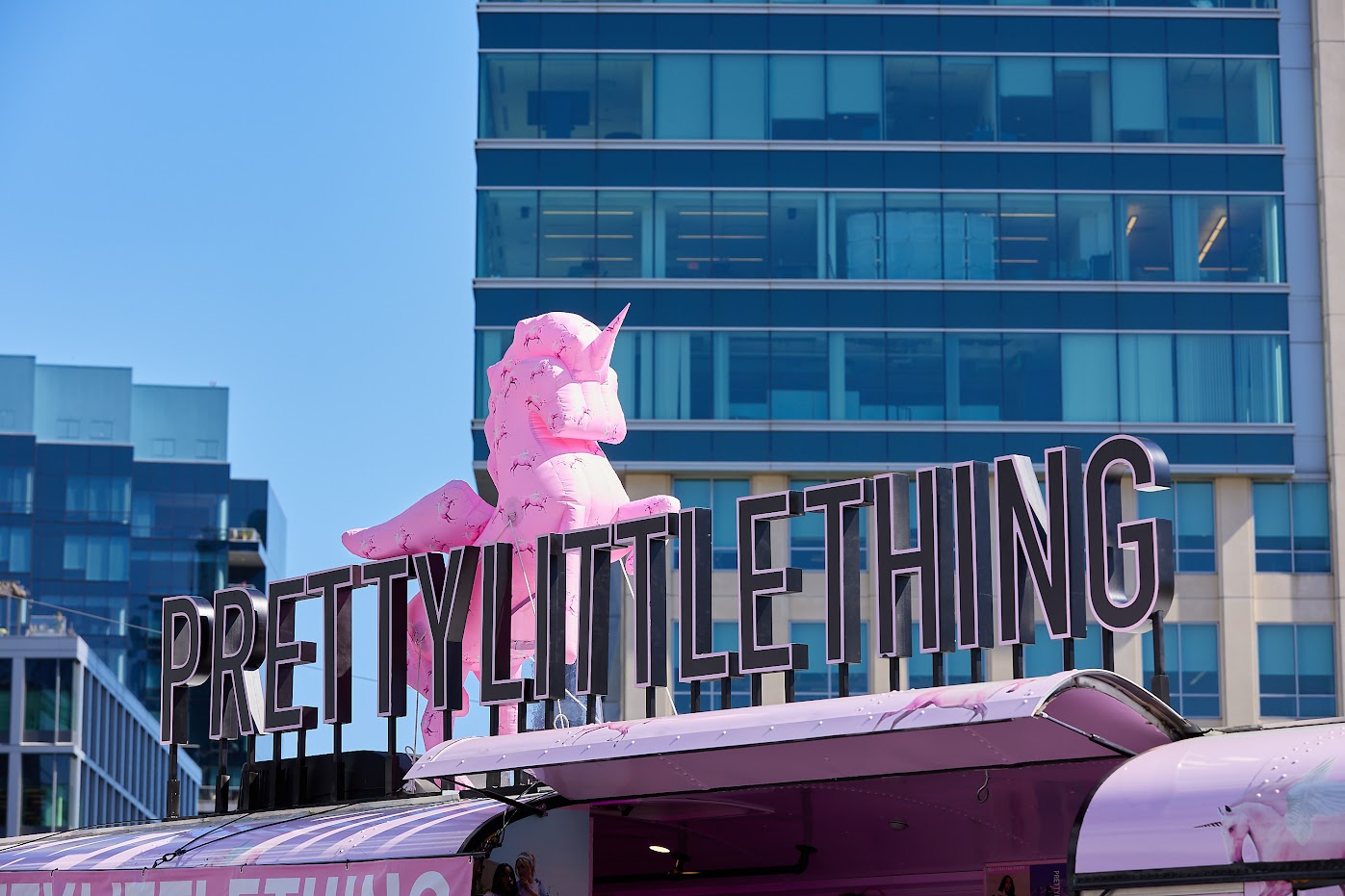 The black PLT sign on top of the bus, with a pink unicorn behind